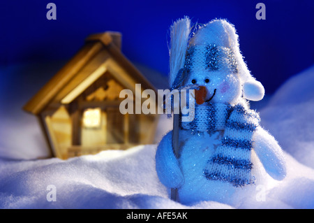 Weihnachten Stillleben Schneemann und ein Holzhaus auf Schnee Weihnachten Weihnachtskarte Stockfoto