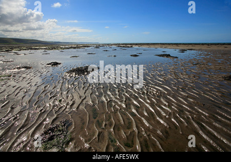 Wellen im Sand und Fels-Pools auf Llanon Strand, Wales. Stockfoto