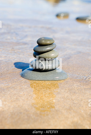 Graue Steinhaufen, balancieren auf einem Sandstrand Stockfoto