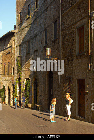 Eine Nebenstrasse führt vom Hauptplatz in San Gimignano Toskana Italien mit Frau im Gespräch mit Kind Stockfoto