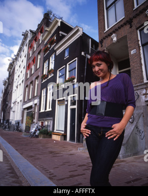 Schöne Holländerin Posen von traditionellen Kanal Seite Gebäude im Zentrum von Amsterdam. Stockfoto