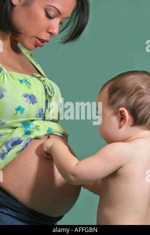 Amerikanische junge Familie ein kleiner Junge küsst Bauch schwangere Mutter Schwangerschaft Mutterschaft Foto vertikal in den USA Stockfoto