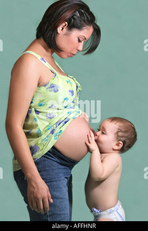 Amerikanische junge Familie ein kleiner Junge küssende Mütter schwangere Bauchschwangerschaft Mutterschaft Foto vertikal in den USA Stockfoto