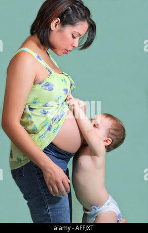 Amerikanische junge Familie ein kleiner Junge küsst Mütter schwangere Bauchschwangerschaft mit Sohn Foto vertikal in den USA Stockfoto