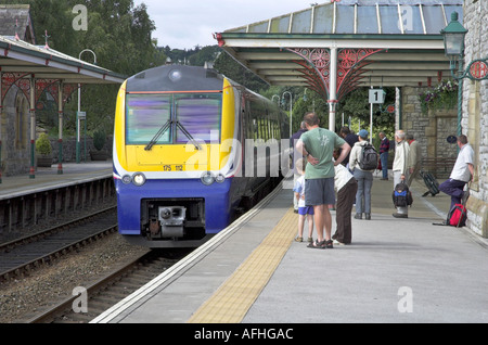 Passagiere, die darauf warten, starten Sie ihre Reise auf einem Bahnsteig Bahnhof für einen ankommenden Zug Stockfoto