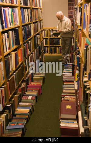 Hay Cinema Bookshop, Mann liest sich alte Bücher aus zweiter Hand. Volle Bücherregale Bücher liegen auf dem Boden. Hay-on-Wye Festival UK 2006 2000s Stockfoto