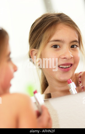 Nette junge Mädchen versucht, auf mamas Lippenstift zum ersten Mal vortäuschen, ein Erwachsener zu werden. Stockfoto