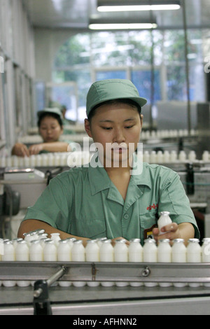 Junge Frau in grüner Uniform und Hut, die an der Milchproduktionslinie der Wahaha Soft Drinks and Water Corporation arbeitet. Stockfoto