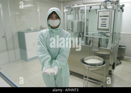 Arbeiter, die bei der Qingchunbao Pharmacutical Corporation in sterilen Bedingungen volle Overalls und Masken tragen, auf der Produktionslinie, die traditionelle Arzneimittel herstellen Stockfoto