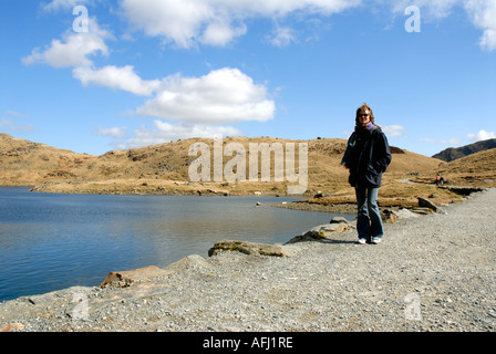 Frau Wanderer Kreuzung Damm über Llyn Llydaw Llwybr y Mwynwyr Bergarbeiter Track Snowdonia Nationalpark Mount Snowdon Yr Wydd Stockfoto