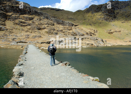 Frau Wanderer Kreuzung Damm über Llyn Llydaw Llwybr y Mwynwyr Bergarbeiter Track Snowdonia Nationalpark Mount Snowdon Yr Wydd Stockfoto