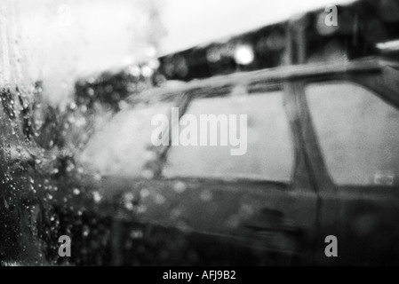 Regentropfen auf Autofenster Blick auf die vorbeifahrenden Autos in der Straße Stockfoto