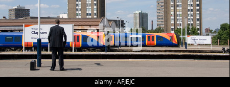 Bahnhof Clapham Junction mit Business-Mann wartet auf Plattform South West Trains & Hochhaus Wohnungen über Stockfoto