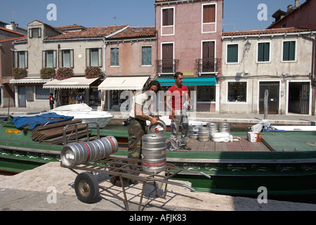 Zwei Männer entladen Fässer Bier vom Boot im Kanal auf der Insel Murano-Italien Stockfoto