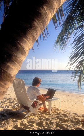Frau arbeitet auf Laptop-Computer am Strand Modellbild veröffentlicht Stockfoto