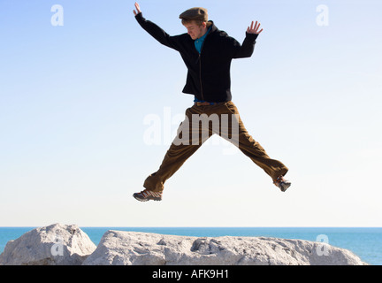 Teenager-Jungen springen auf Felsen am Seeufer des Lake Michigan Stockfoto