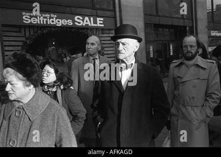 Mann mit Hut und Schleife, der in einer Busschlange in der Oxford Street vor Selfridges wartet. Erster Tag der Neujahrsverkäufe 1976 HOMER SYKES Stockfoto
