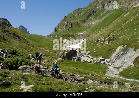 Wanderer, die Verhandlungen über einen Stream in die Combe De La Neuva, Beaufortain, Savoie, trail französische Alpen auf der Tour du Beaufortain Stockfoto