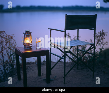 Gin und Tonic durch einen Hurrikan-Lampe, Blick auf den Sambesi, Old Mondoro Buschcamp, Sambia Stockfoto