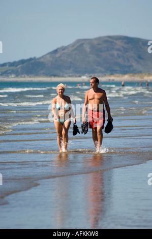 Ein Alter Ehepaar mittleren Wandern paddeln am Ynyslas Strand und Sand im Meer, wales Borth Ceredigion UK an einem Sommernachmittag Stockfoto