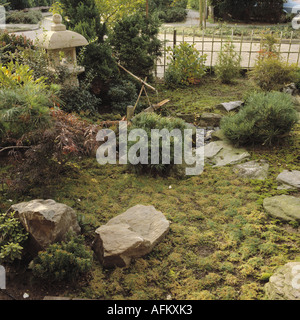 Große natürliche Felsen und kleinen Bambus Wasserspiel im orientalisch anmutenden Garten mit japanischen Steinlaterne und niedrigwüchsige Koniferen Stockfoto