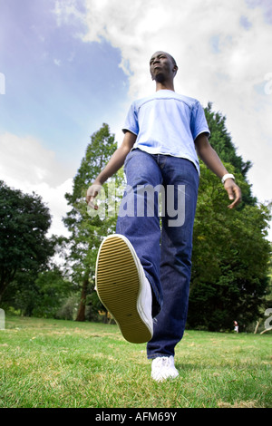 Young Black Mann zu Fuß auf dem Rasen mit einem big foot Stockfoto
