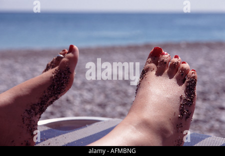 Weibliche Füße auf einem Liegestuhl am Meer Stockfoto