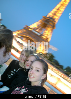 Drei Studentinnen posieren am Flussboot Kreuzfahrt mit verschwommenen Eiffelturm hinter Paris Frankreich Stockfoto