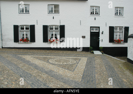 Gepflasterte Straße mit Mosaik Muster und Front-Fassade des typisch weiß getünchten Haus im Dorfzentrum von Thorn Niederlande Stockfoto