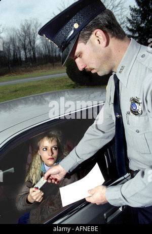 Polizist gibt Strafzettel an eine junge Fahrerin Stockfoto