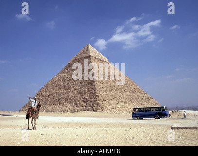 Gizeh und Kairo entfernte antike Pyramide und kontrastreiche Reiseformen mit geparkten modernen blauen Reisebus von der Stadt und einheimischer Mann auf Kamel in der Wüste Stockfoto