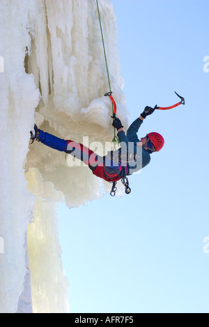 Eiskletterer klettern auf Eiswand mit Eispickel und Steigeisen , vorbei an einem Überhang , Finnland Stockfoto