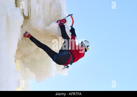 Weibliche Eiskletterin klettert auf der Eiswand mit Eispickel und Steigeisen, Finnland Stockfoto