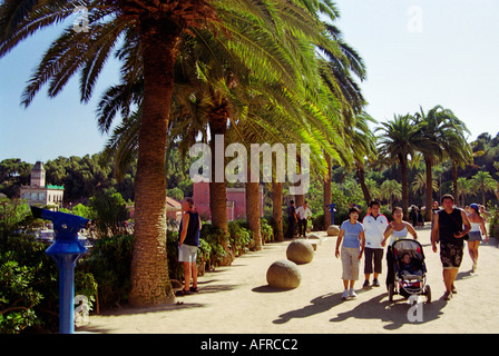 Besucher flanieren durch die Palmen in Antoni Gaudís Landschaft Park Parc Güell in Barcelona Spanien Stockfoto