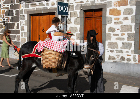 Junges Mädchen reitet auf einem Esel in der Nähe von Taxischild auf Fiesta del Pino in Teror auf Gran Canaria. Stockfoto