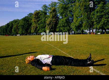 Der betrunkene Student lag ohnmächtig und schlief ihn auf den Spielfeldern ab, nachdem er die ganze Nacht wach war. HOMER SYKES AUS DEN 1990ER JAHREN Stockfoto