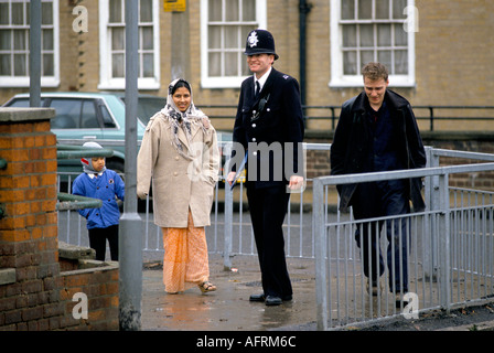 Polizist unterhält sich mit einer asiatischen Mutter und ihrem Kind. East End London. Der Polizist trägt ein Klemmbrett. England um 1995 UK 1990s. Stockfoto