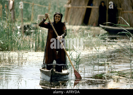 Marsh Araber, Südirak. Marsh Arab Woman steht im Boot und rudert zwischen den traditionellen Schilfeinseln der mesopotamischen Marshes 1980er 1984 HOMER SYKES Stockfoto