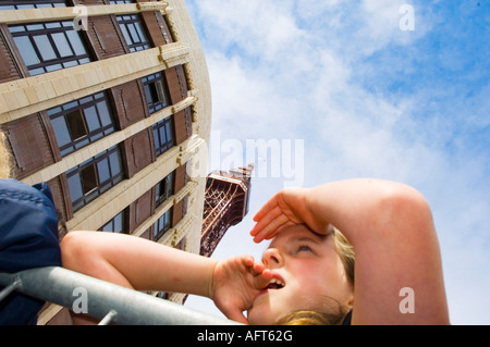 Junges Mädchen, das sich über Barrierehäude stützt und die Augen vor der Sonne schützt Stockfoto