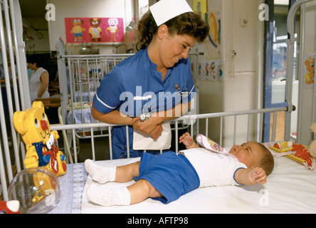 Personal-Krankenschwester in der Kinderstation im Alder Hey Children's Hospital Liverpool NHS Hospital. UK England Krankenschwester mit Baby im Babybett. 1988 HOMER SYKES Stockfoto