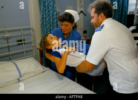 Männliche und weibliche Krankenschwestern heben Kind auf Bett Kinderstation Alder Hey Children's Hospital Liverpool 1980s NHS 1988 UK HOMER SYKES Stockfoto