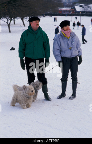 Snow UK 1990 s Primrose Hill Winter in London gekleidet für kaltes Wetter Paar mit Hunden 90 s 1991 HOMER SYKES Stockfoto