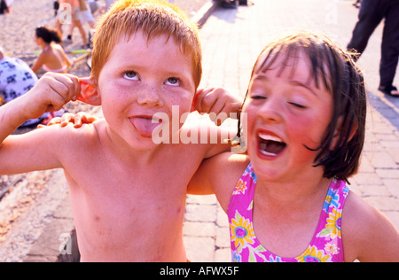 Zwei Kinder, ein kleiner Junge zieht ein lustiges Gesicht, der Junge hat große rote Ohren und seine ältere Schwester denkt, er sei sehr lustig. Brighton, East Sussex, England Großbritannien Stockfoto