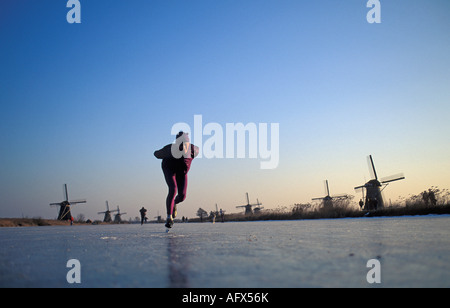 Niederländischen Kinderdijk Mann auf Eis vor Windmühlen Stockfoto