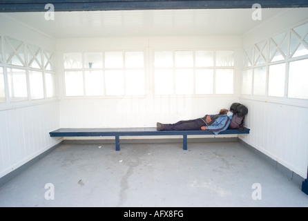 Obdachloser auf Bank in der Öffentlichkeit schlafend shelter Aberystwyth, Wales Stockfoto