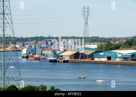 Die Schiffe legen in Lagern am Flussufer der Ipswich Docks unterhalb von National Grid an Hochspannungsmasten und Kabeln an, die den Fluss Orwell Suffolk UK überspannen Stockfoto