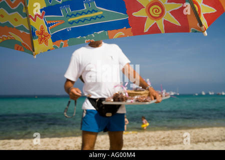 Plage de Pampelonne - St Tropez, Frankreich. Ansicht von Sonnenschirm umrahmt. Mann, Verkauf von Süßigkeiten am Strand Stockfoto