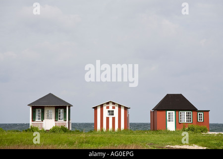 Drei individuelle drei bunte kleine Strandhäuser in der Regel Dänisch und jeweils sehr unterschiedliche inmitten Grüne Düne Grasss Linie die werden Stockfoto