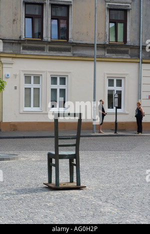Bronze-Stuhl, Holocaust-Mahnmal, auf Platz im ehemaligen jüdischen Ghetto, Bezirk Podgorze, auch zwei Leute lesen Zeichen, Krakau, Polen Stockfoto