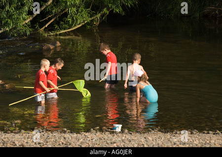 Kleinkinder mit Fischernetzen Paddeln im Fluss bei Denton Holme Carlisle Cumbria UK Stockfoto